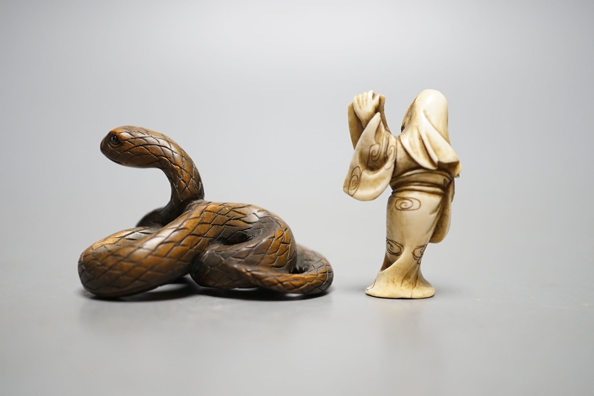 A Japanese ivory figure of a sage and a signed carved wood snake netsuke, 5cm long